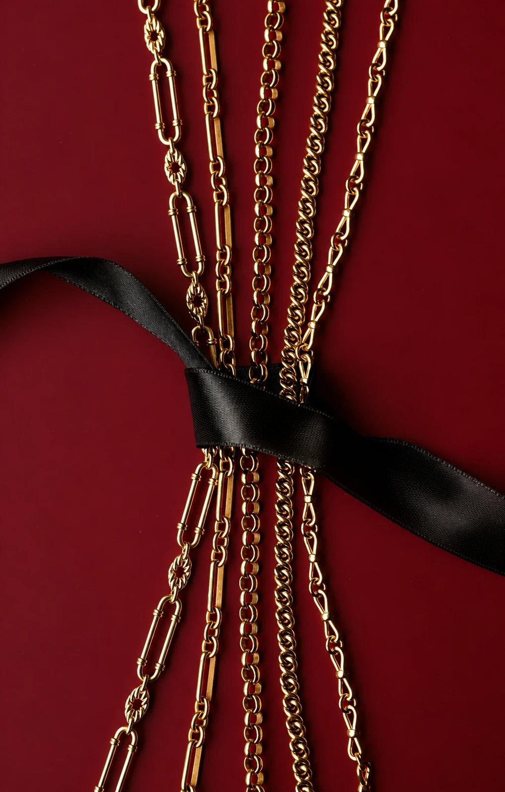 Gold chains gathered with a black ribbon bow on deep red