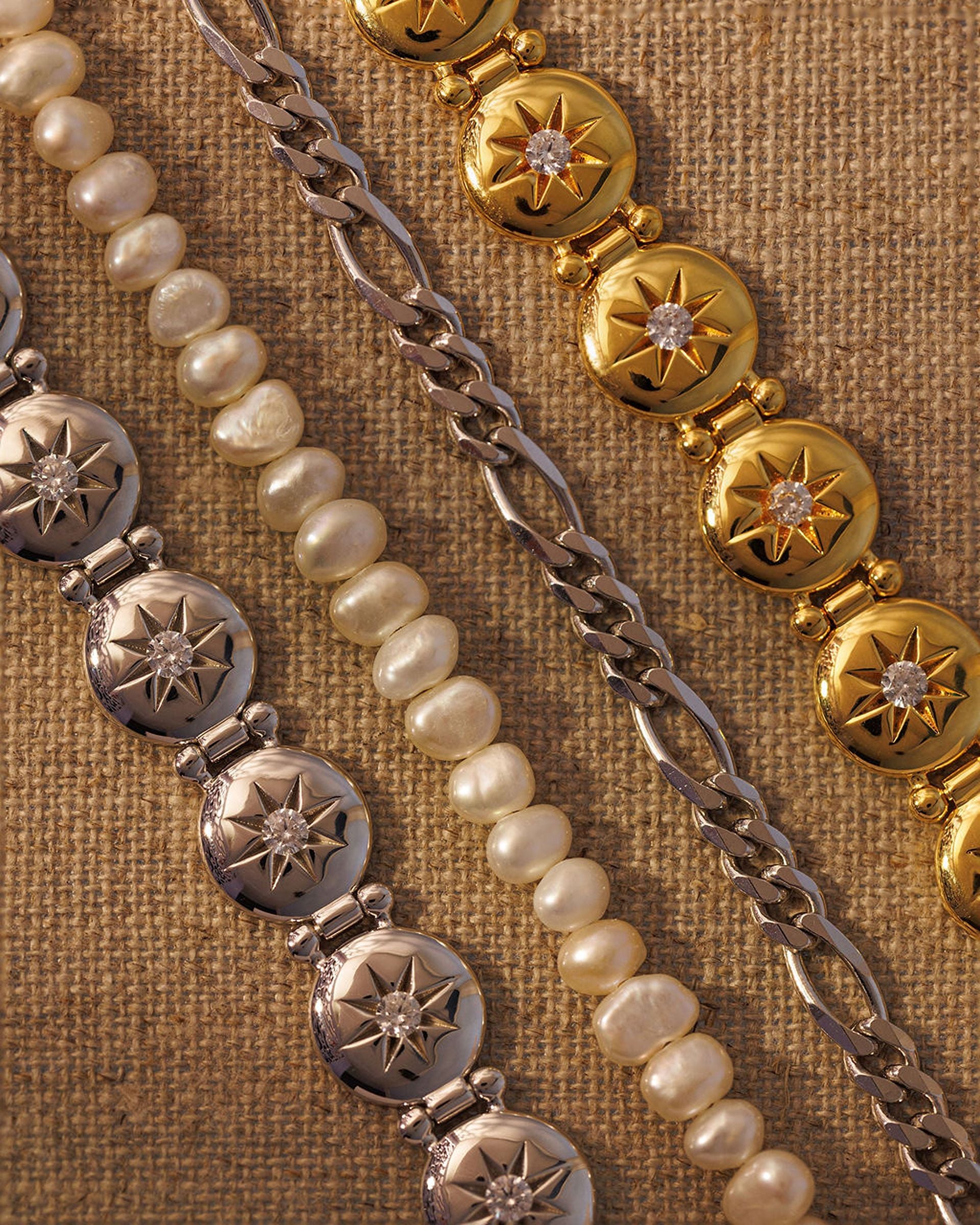Mixed metal bracelet stack with gold, silver, pearl and chain bracelets layered together