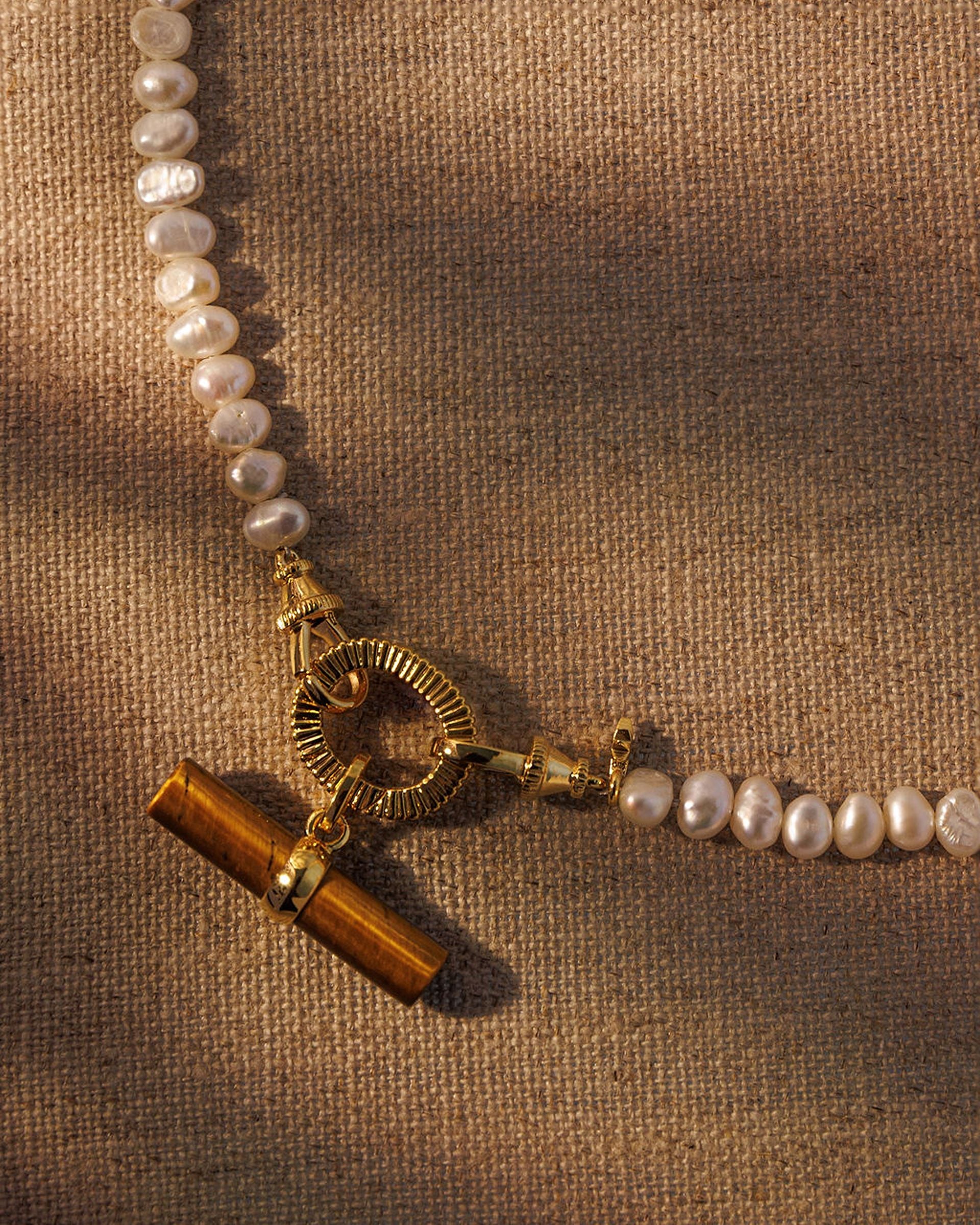 Baroque pearl necklace with tiger’s eye T-bar pendant attached to gold oval clasp
