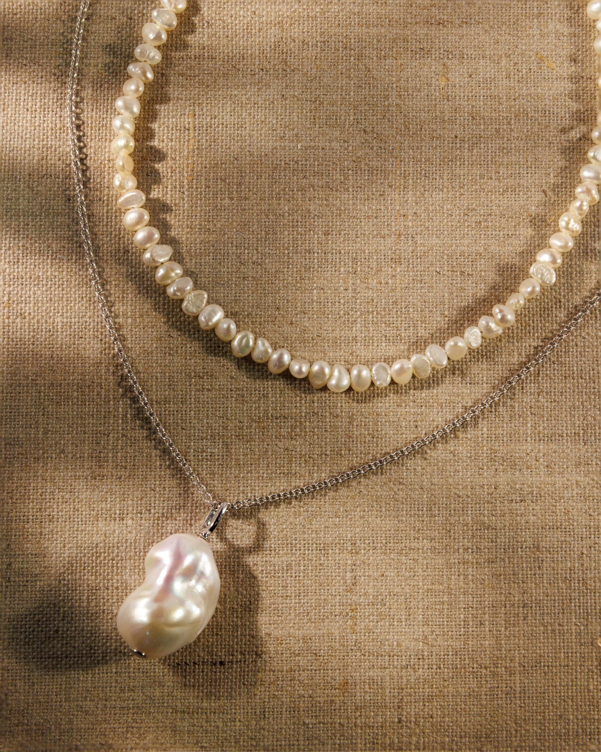 A baroque pearl necklace, fine silver chain and pearl pendant. Antique-inspired demi-fine jewellery designed to layer, connect and restyle.