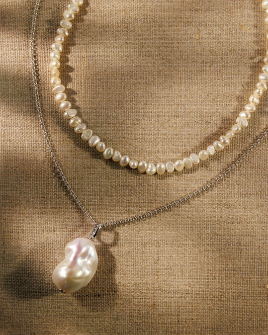 A baroque pearl necklace, fine silver chain and pearl pendant. Antique-inspired demi-fine jewellery designed to layer, connect and restyle.