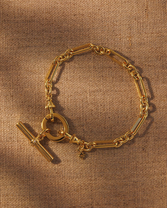 Gold paperclip chain bracelet with T-bar pendant attached to oval clasp