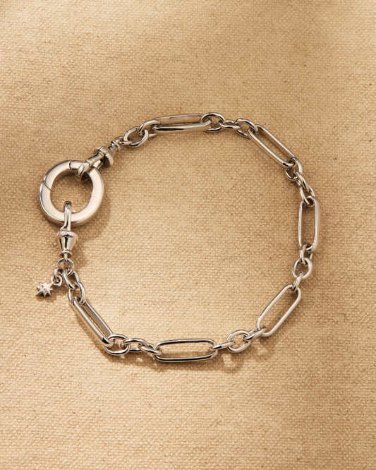 Silver paperclip chain bracelet with oval clasp designed for layering and attaching charms