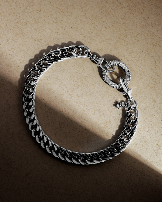 Chunky sterling silver chain bracelet with oval clasp and lobster fastening on textured background