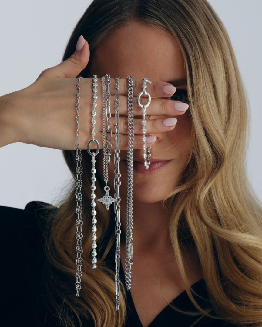 Fleur De Force holding layered silver chain necklaces and pendants showing multiway styling