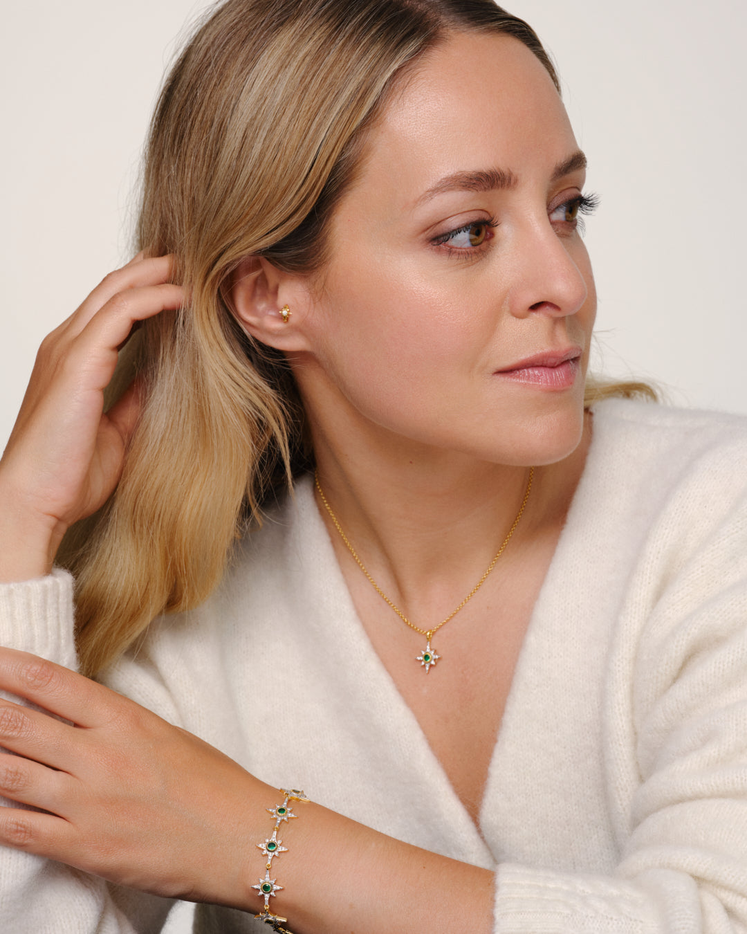 Fleur de Force wearing gold bracelet and necklace set with green crystals designed to stack or connect using oval clasp multiway jewellery
