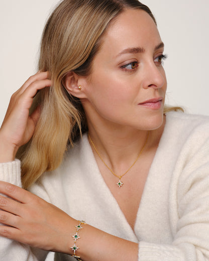 Fleur de Force wearing gold bracelet and necklace set with green crystals designed to stack or connect using oval clasp multiway jewellery