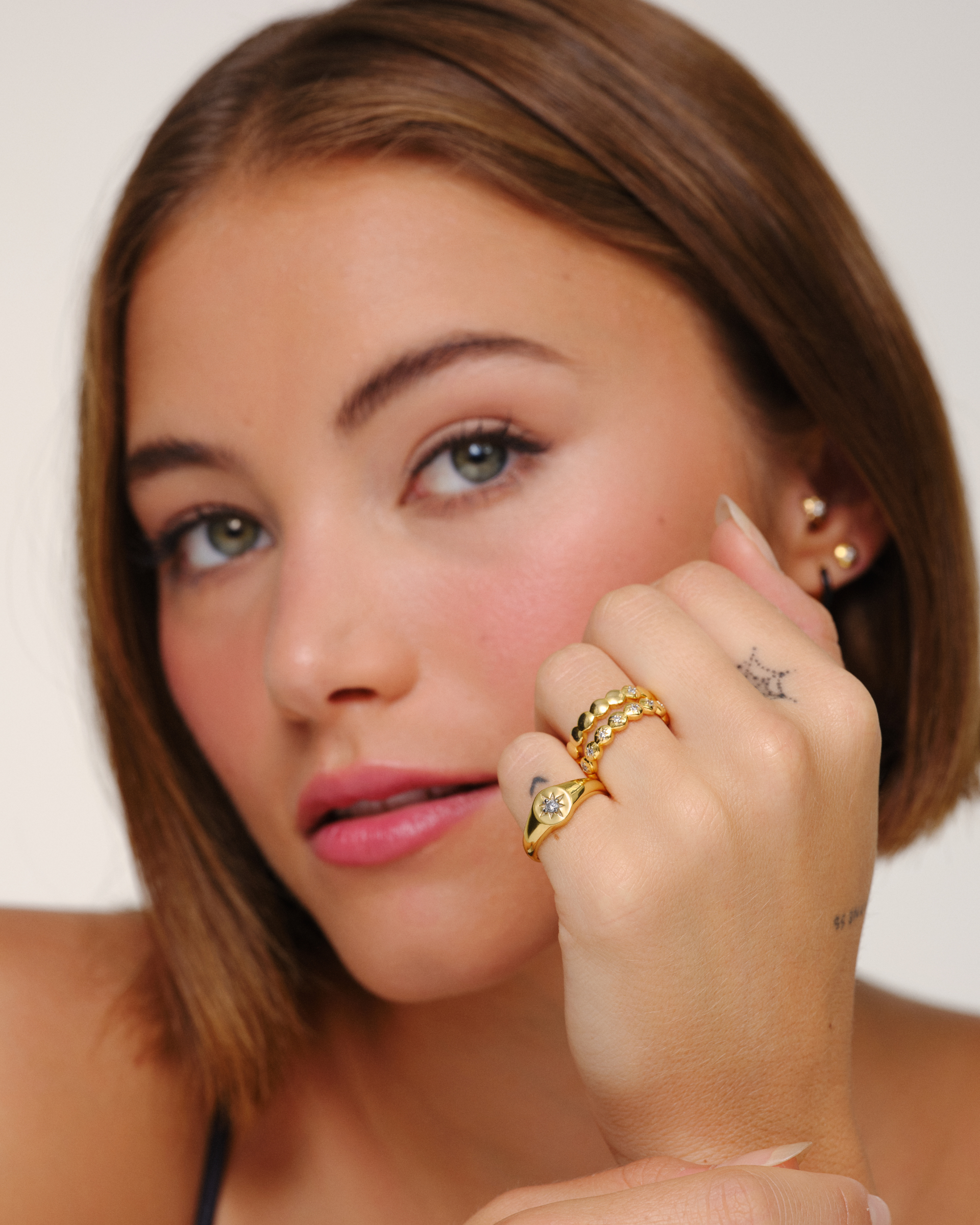 Model wearing gold stacking rings worn together including Ines star ring layered with Cece signet ring
