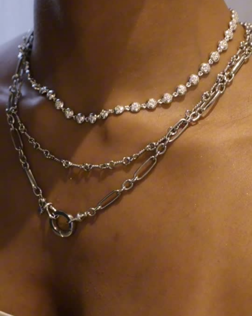 Layered silver necklaces with chains and pendants styled together