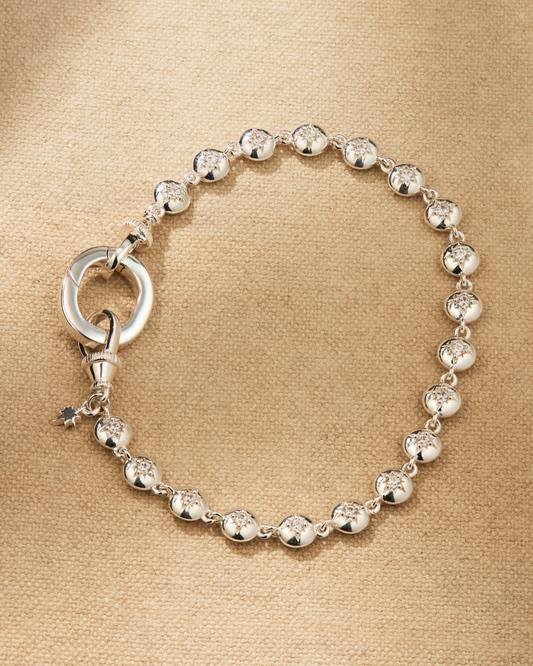 Silver tennis bracelet with central oval link designed for attaching pendants and connecting to other pieces