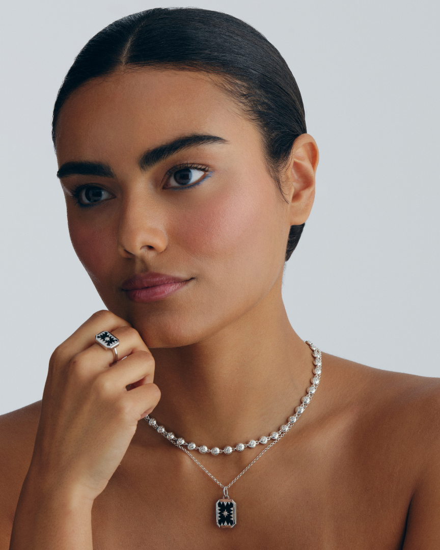 A layered silver necklace set featuring a talisman pendant, fine chain and crystal link necklace. Designed to wear together or style separately. Worn by model.