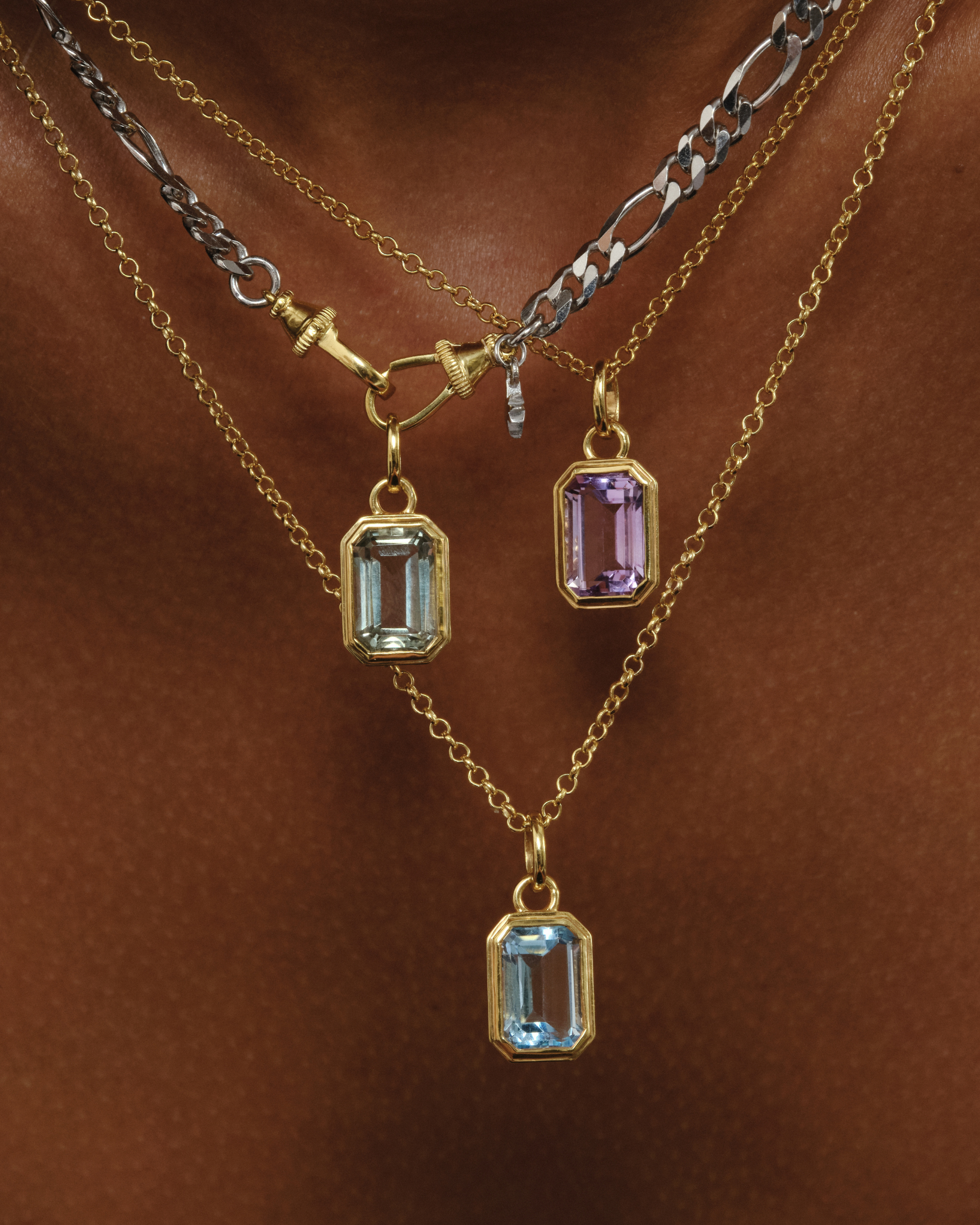 Lumi layered gold and silver chain necklaces styled with emerald cut blue topaz, green amethyst and pink amethyst pendants