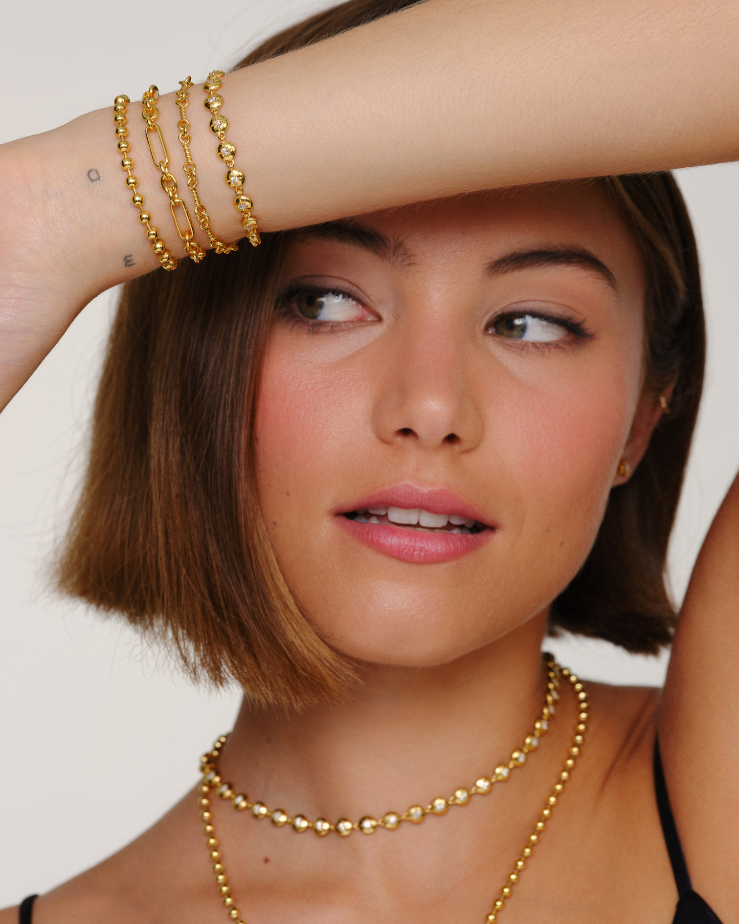 Model wearing gold Claudia, Bella and Luca bracelets stacked with Lulu necklace