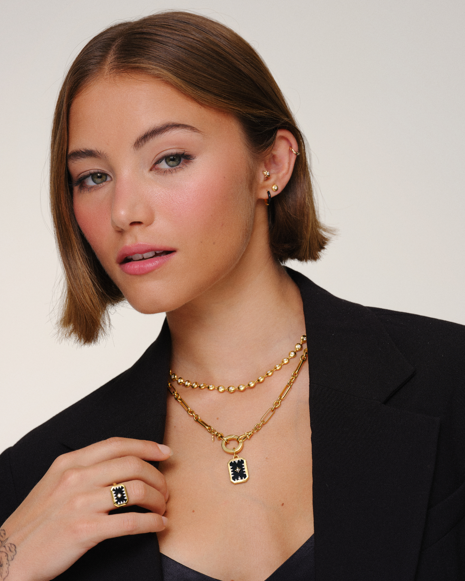 Model wearing layered gold necklaces with paperclip chain, tennis necklace and black onyx pendant for everyday jewellery layering