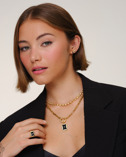 Model wearing layered gold necklaces with paperclip chain, tennis necklace and black onyx pendant for everyday jewellery layering