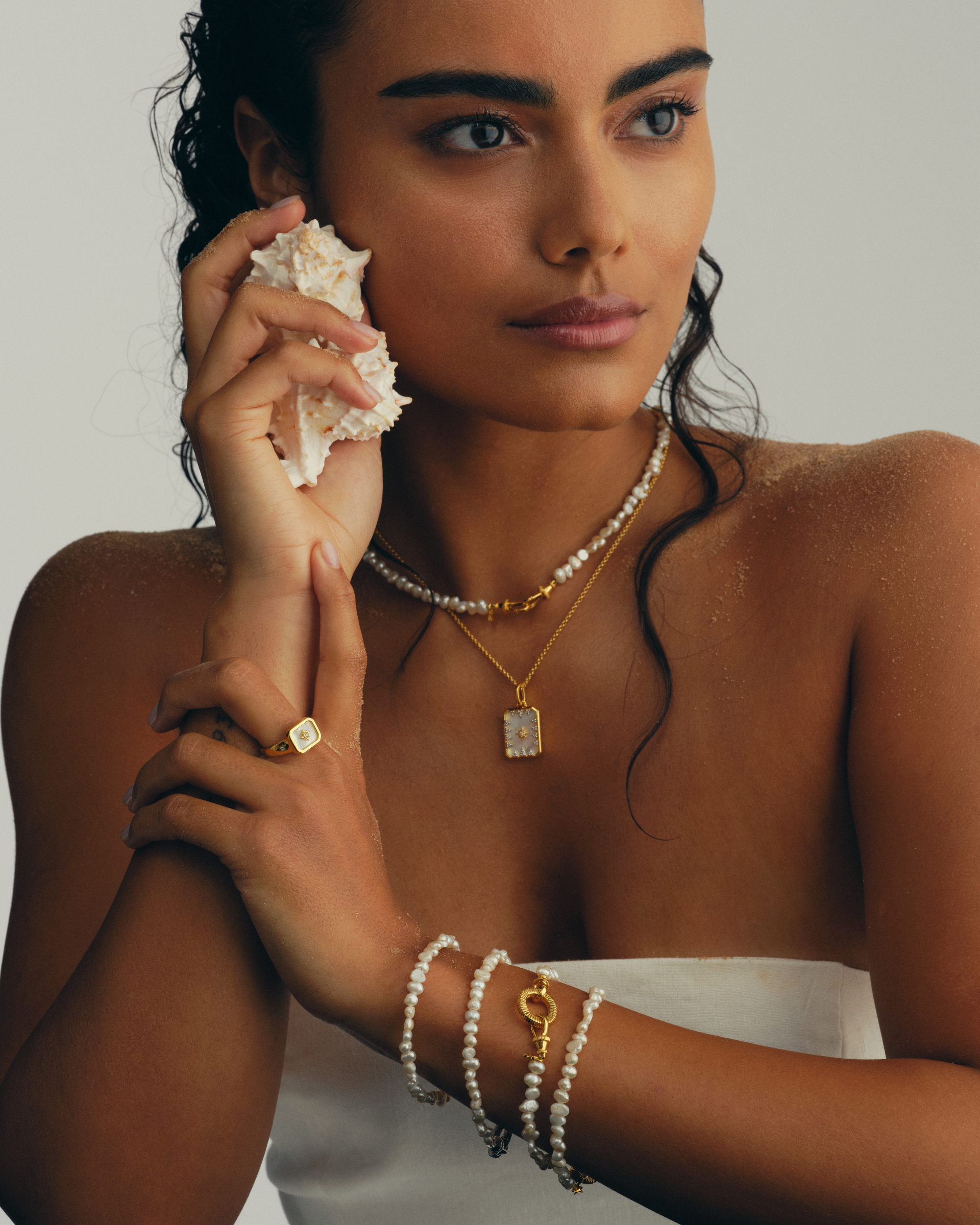 Model wearing gold plated baroque pearl multiway bracelets with oval clasp and layered pearl jewellery