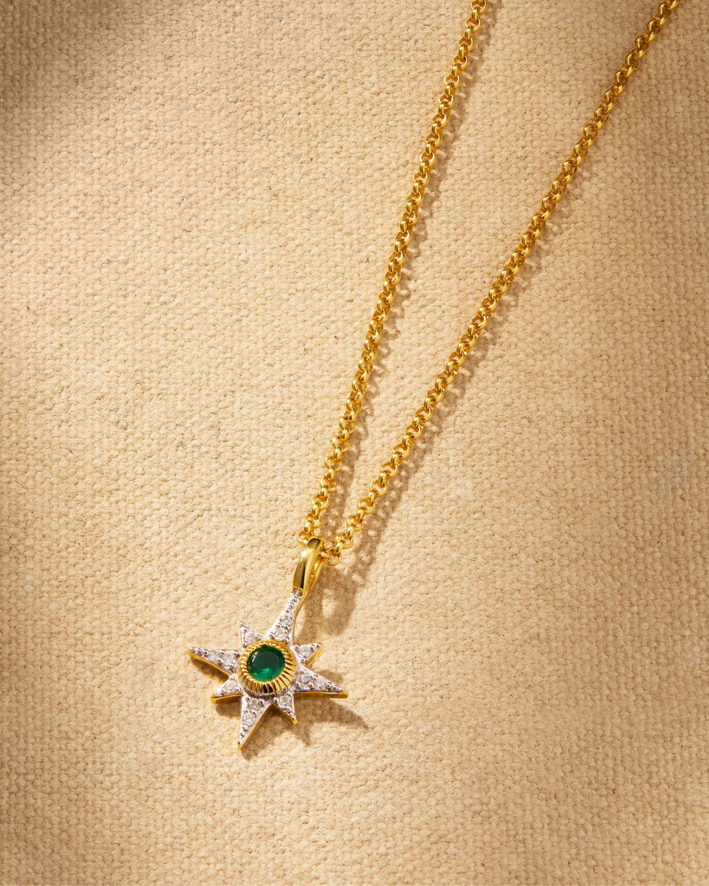 A delicate NORTH STAR pendant necklace with a emerald green crystal detail on a gold chain