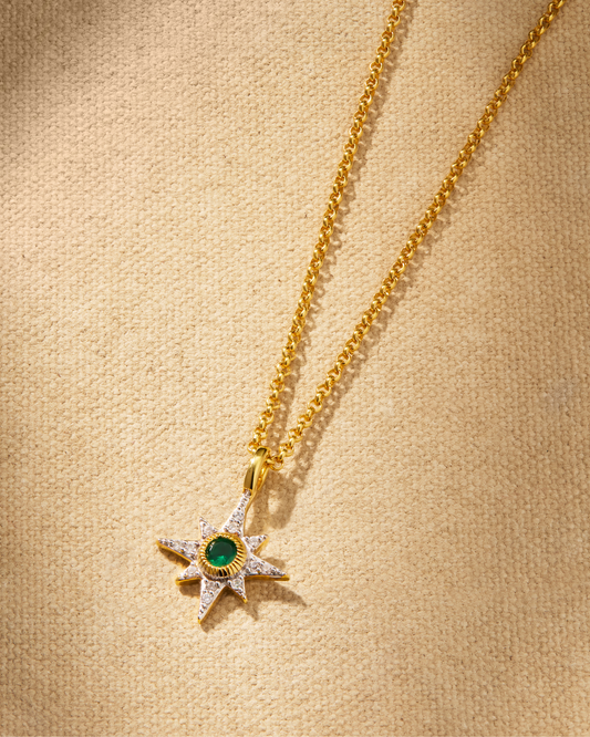 A delicate NORTH STAR pendant necklace with a emerald green crystal detail on a gold chain