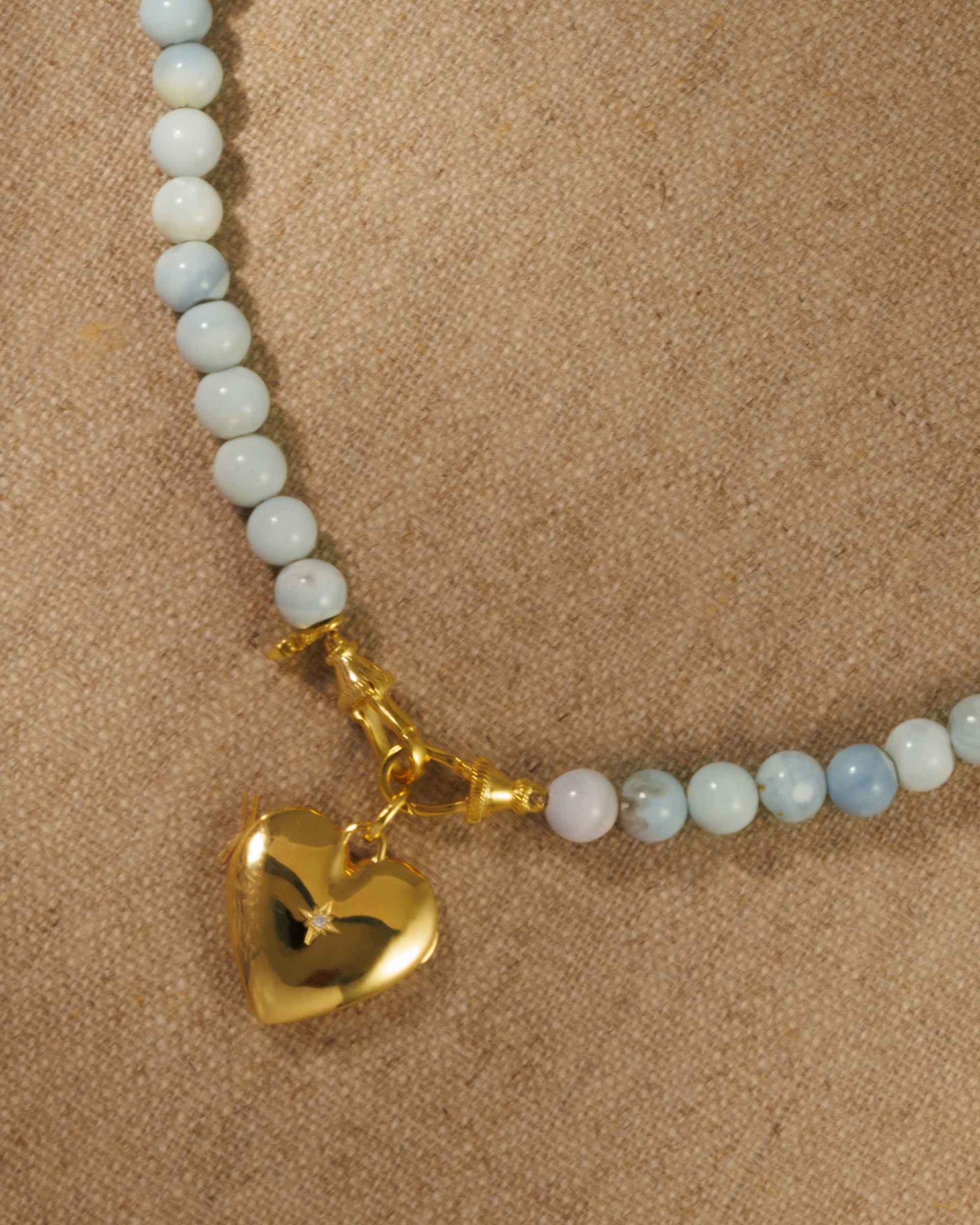 Raven James Cora Pendant on Skye Necklace - 18ct gold plated heart locket with starburst crystal detailing on a natural Peru Blue Opal beaded necklace with signature oval clasp
