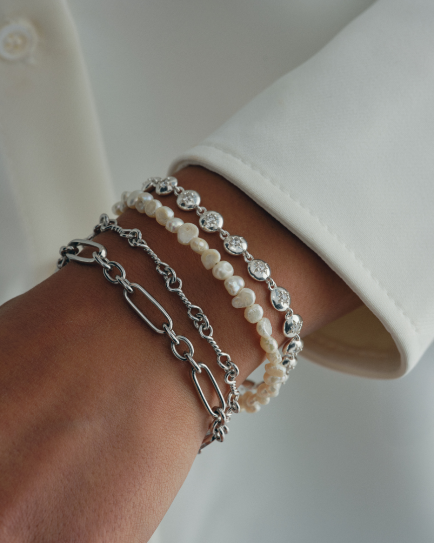 Layered silver chain and pearl bracelet stack with oval clasp