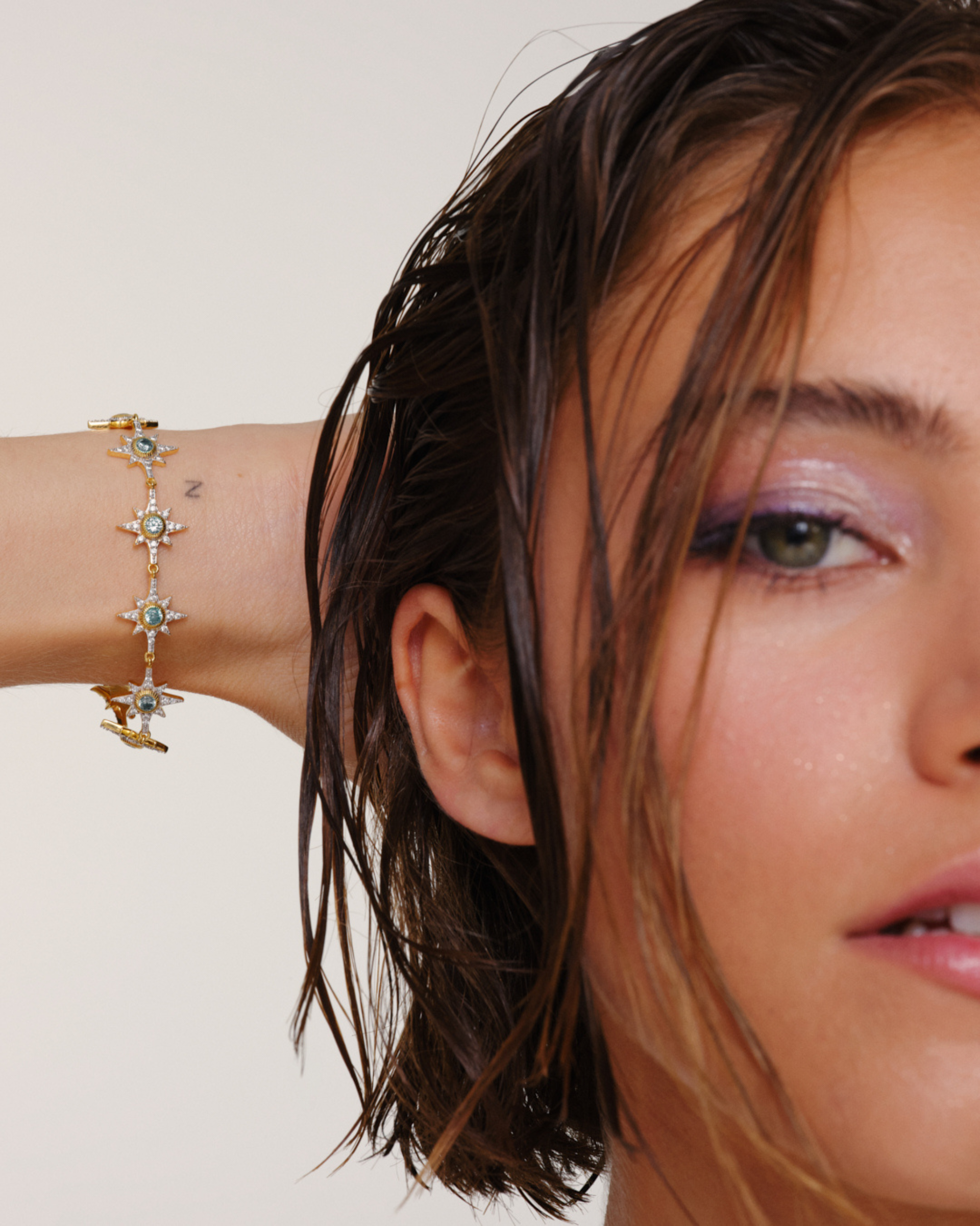 Model wearing gold bracelet with aqua crystals and star design layered multiway jewellery styling