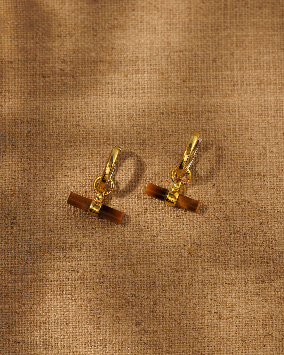 A pair of mix metal hoop earrings with tiger eye t bar charms