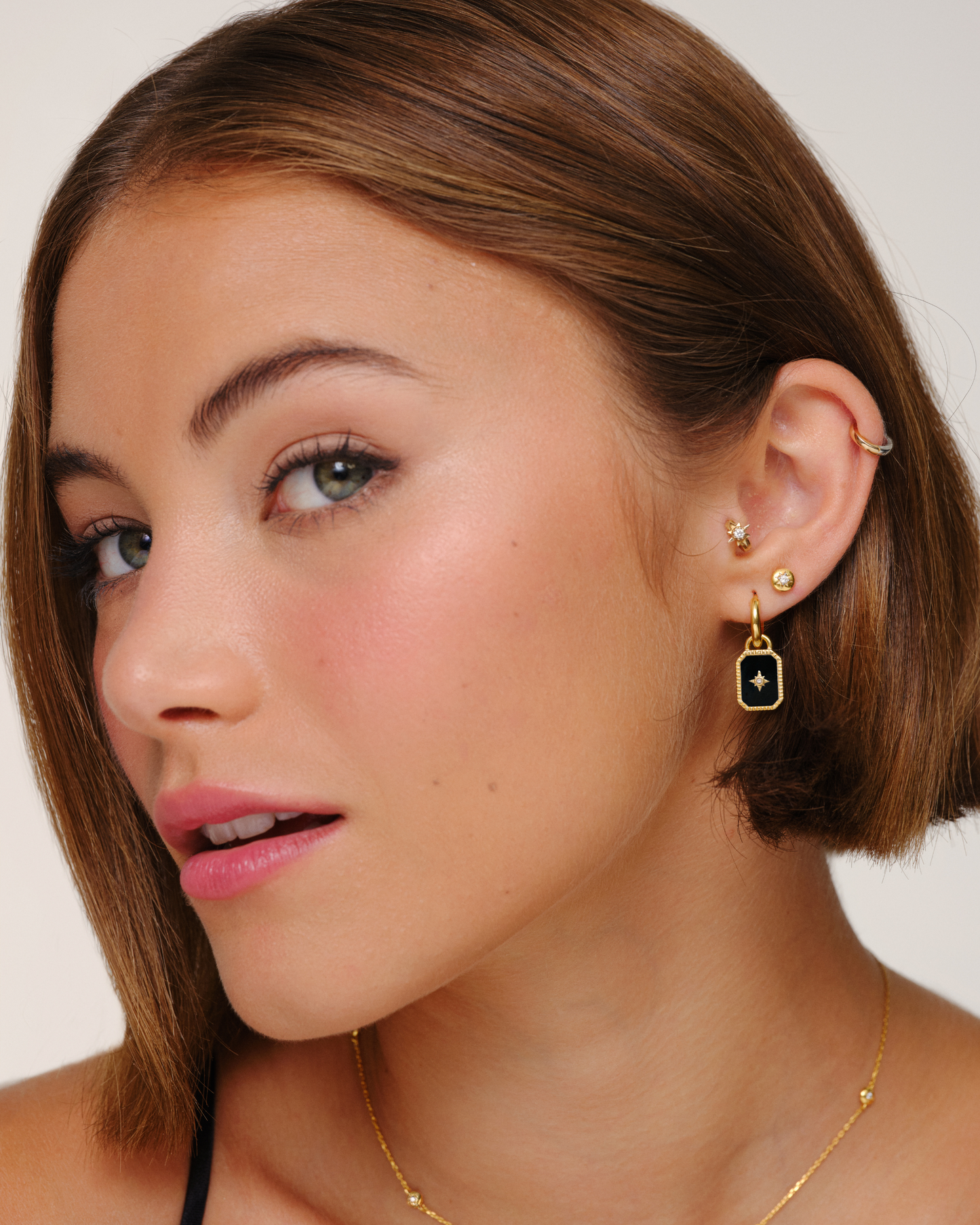 Model wearing gold earring charms with black onyx and crystal detailing on hoop earrings interchangeable jewellery styling