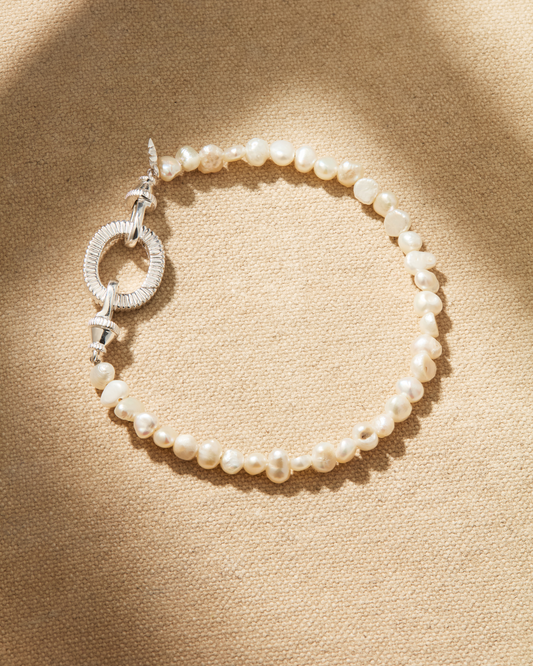 A silver bracelet featuring a single strand of baroque pearls with a silver antique-inspired lobster clasp, designed for multiway styling and adding pendants