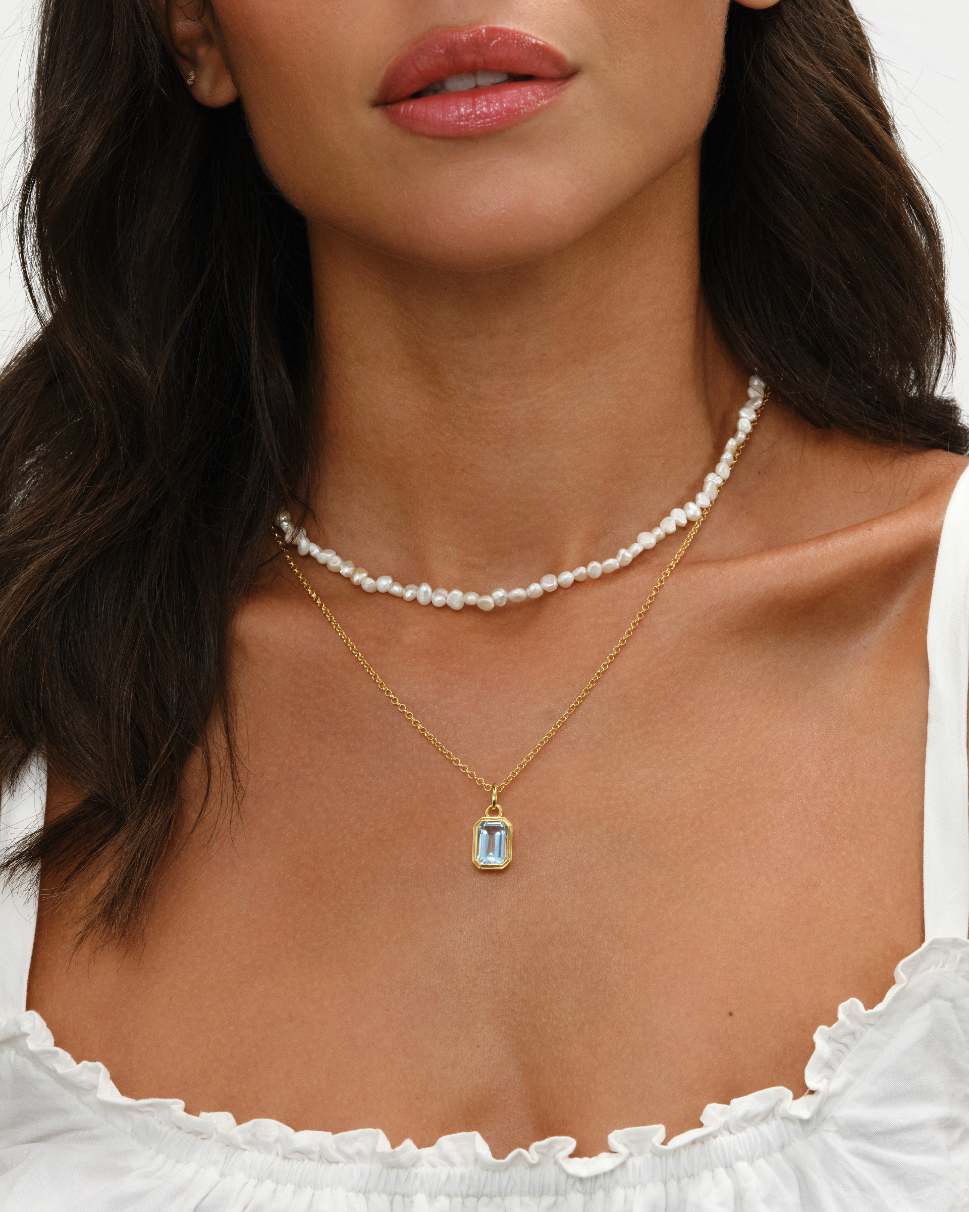 Aura baroque cultured pearl necklace layered with Lumi emerald cut blue topaz pendant on an 18ct gold chain necklace set