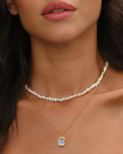 Aura cultured baroque pearl necklace layered with Lumi an emerald cut blue topaz pendant on an 18ct gold chain necklace set