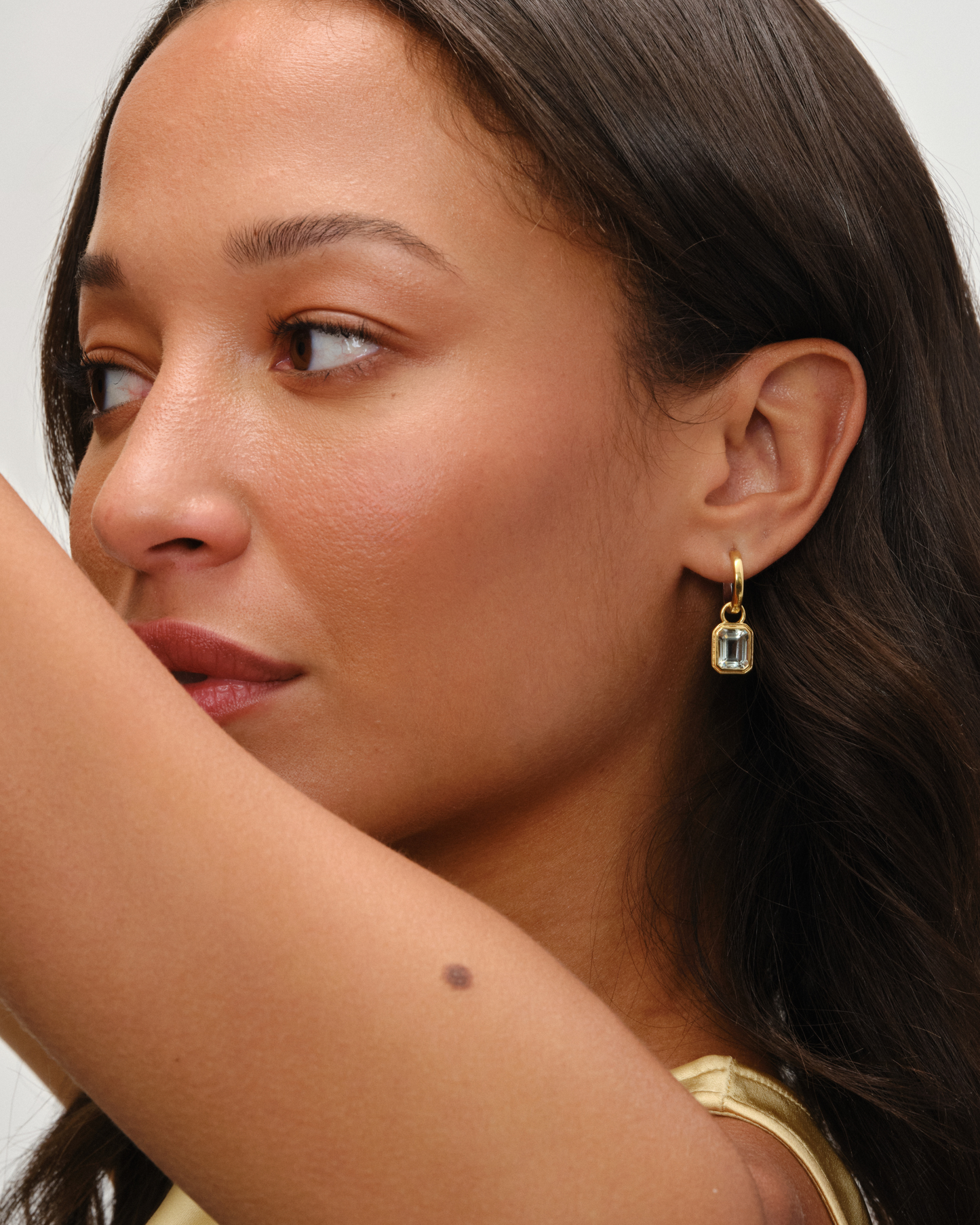 Cara reversible huggie hoop earrings styled with Lumi emerald cut green amethyst charm in 18ct gold