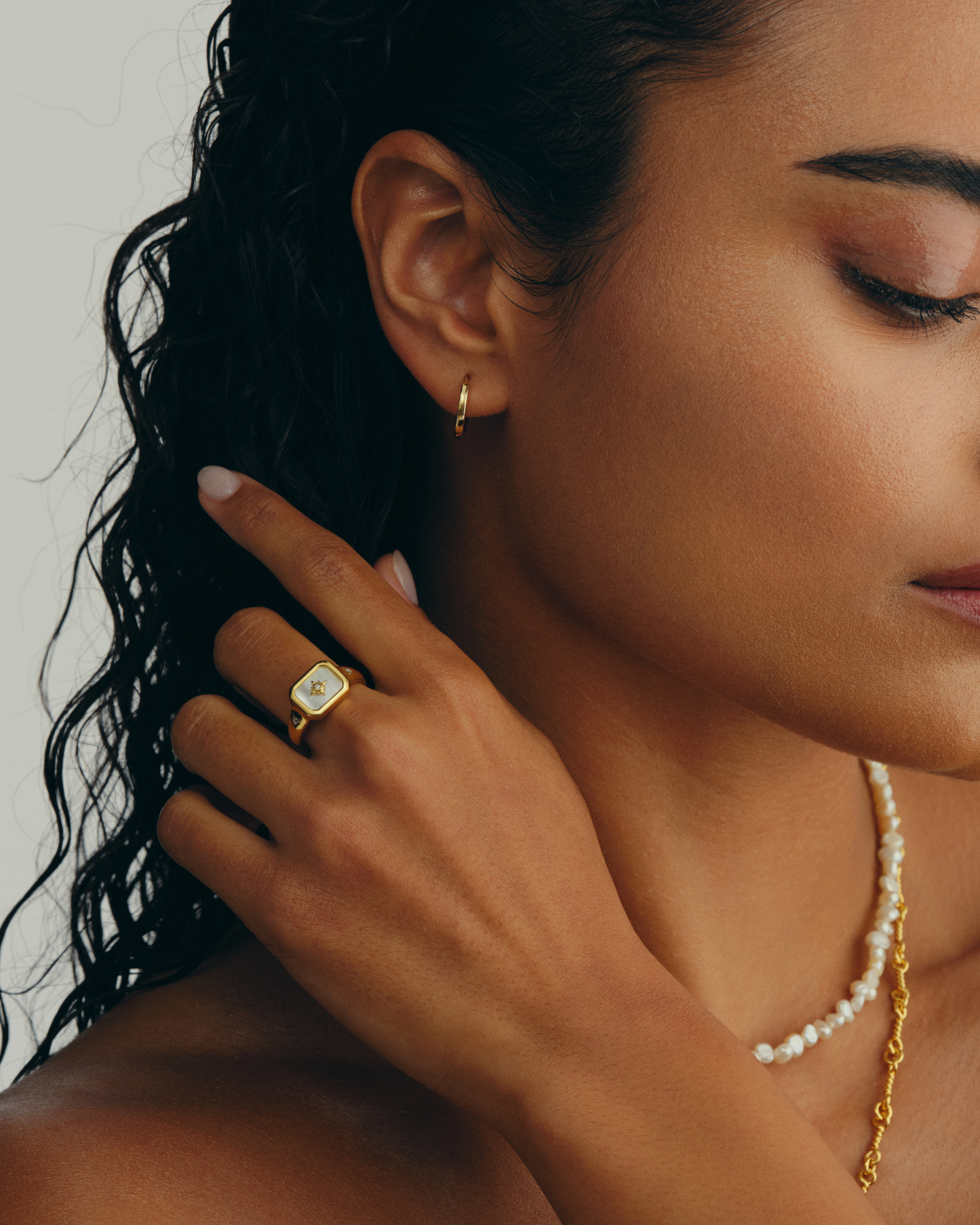 Model wearimg gold signet ring with mother of pearl face and cubic zirconia star detail