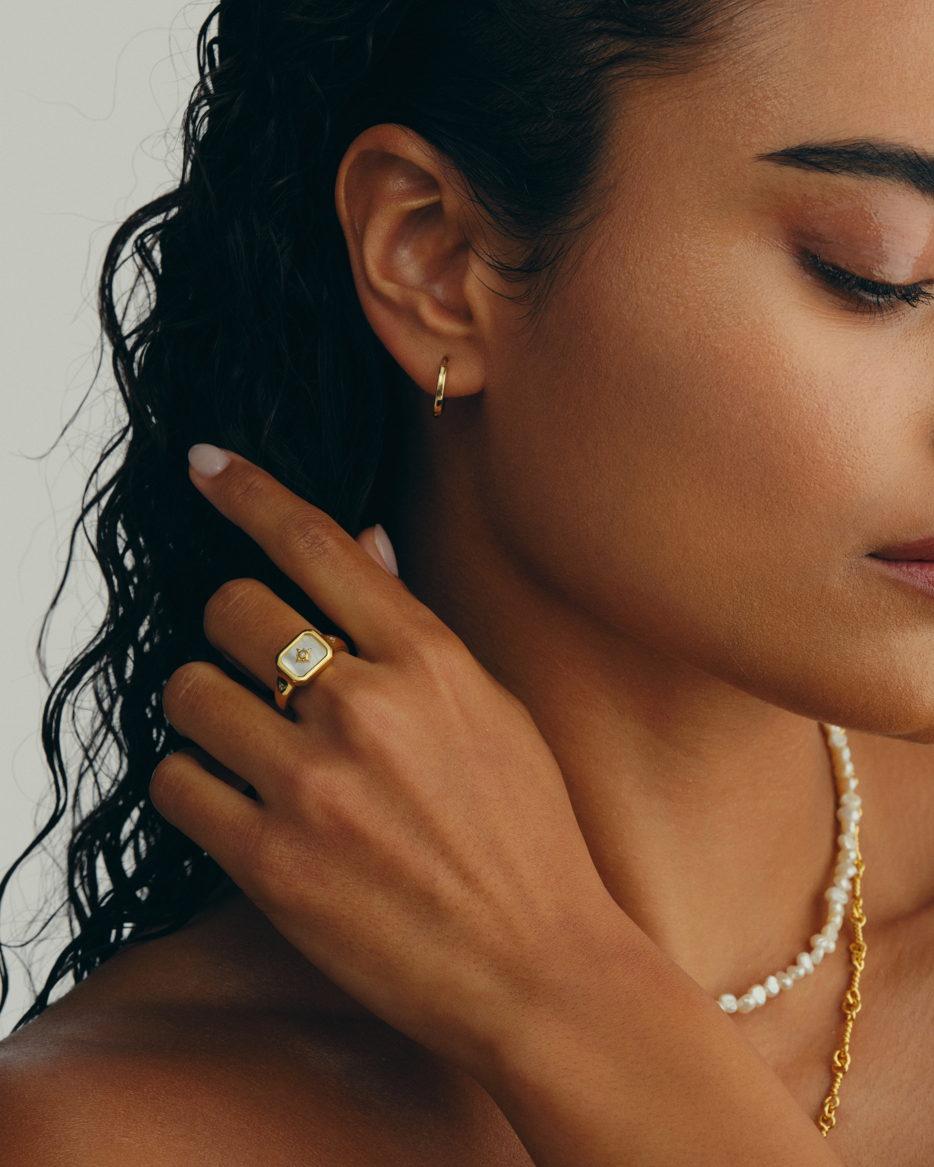 Model wearimg gold signet ring with mother of pearl face and cubic zirconia star detail
