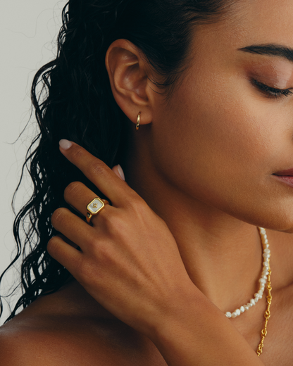 Model wearimg gold signet ring with mother of pearl face and cubic zirconia star detail