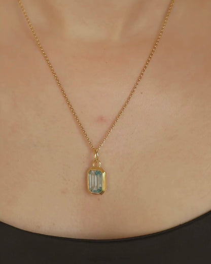 Lumi 18ct gold plated emerald cut blue topaz pendant styled on an ivy gold chain necklace