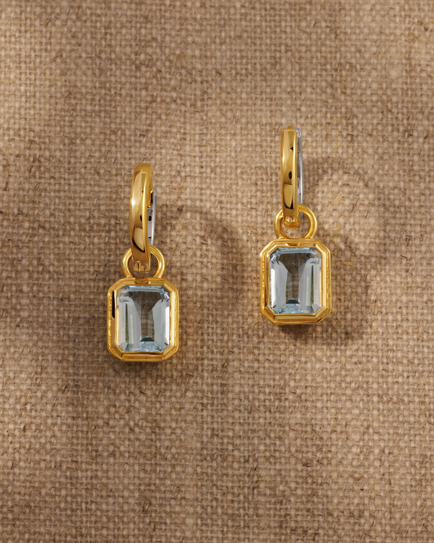 Cara reversible huggie hoop earrings styled with Lumi emerald cut blue topaz charm in 18ct gold