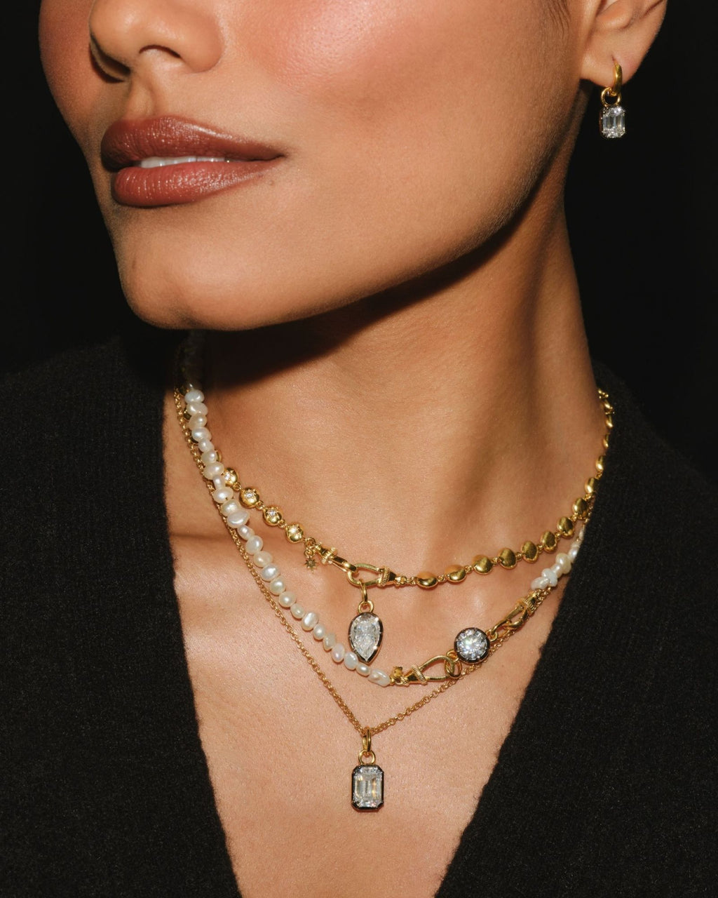 EDITH emerald cut moissanite pendant layered with PIA pear and ODETTE round moissanite pieces, worn with EDITH earring charms