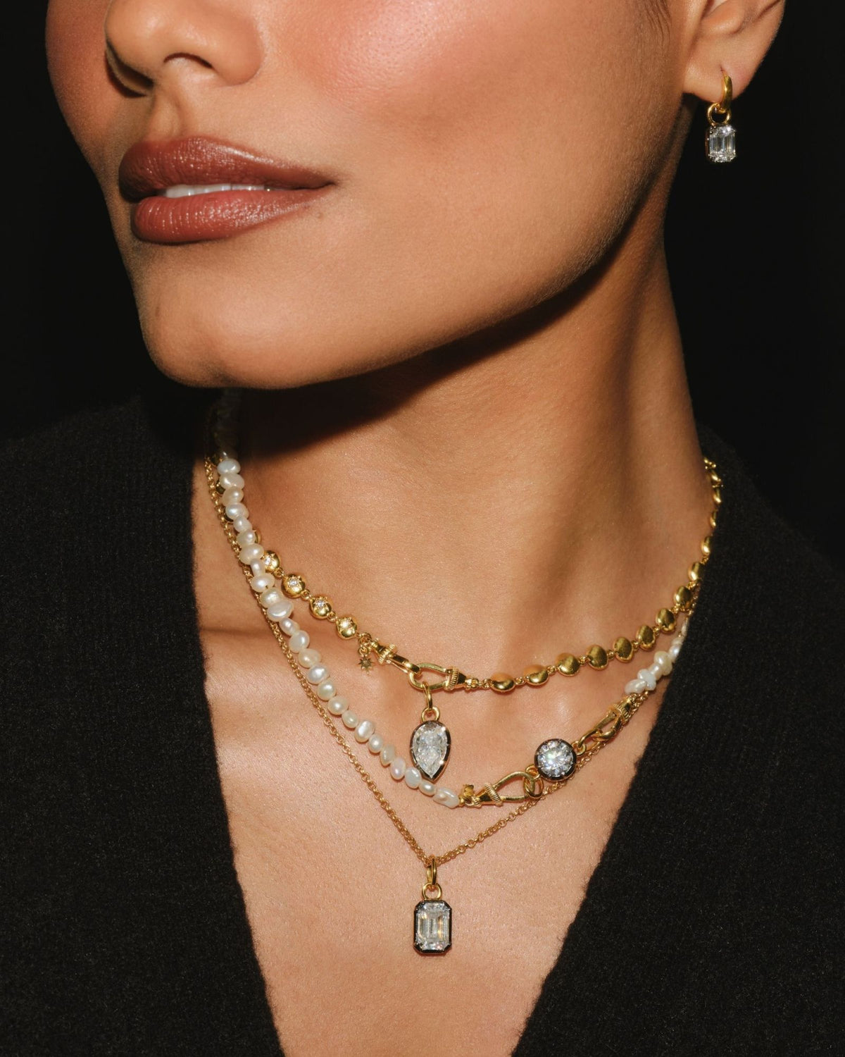 EDITH emerald cut moissanite pendant layered with PIA pear and ODETTE round moissanite pieces, worn with EDITH earring charms