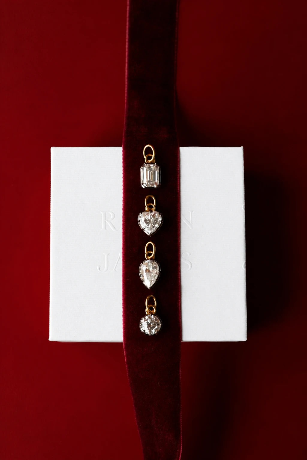 Solitaire moissanite pendants on a velvet ribbon over a white Raven James box