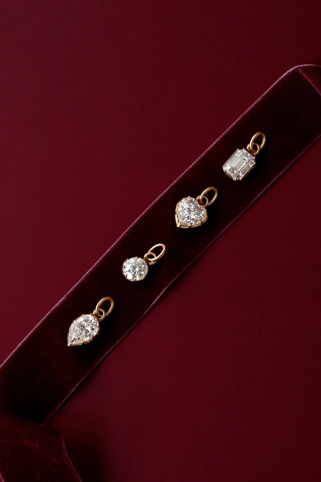 Solitaire moissanite pendants on a velvet ribbon against deep red